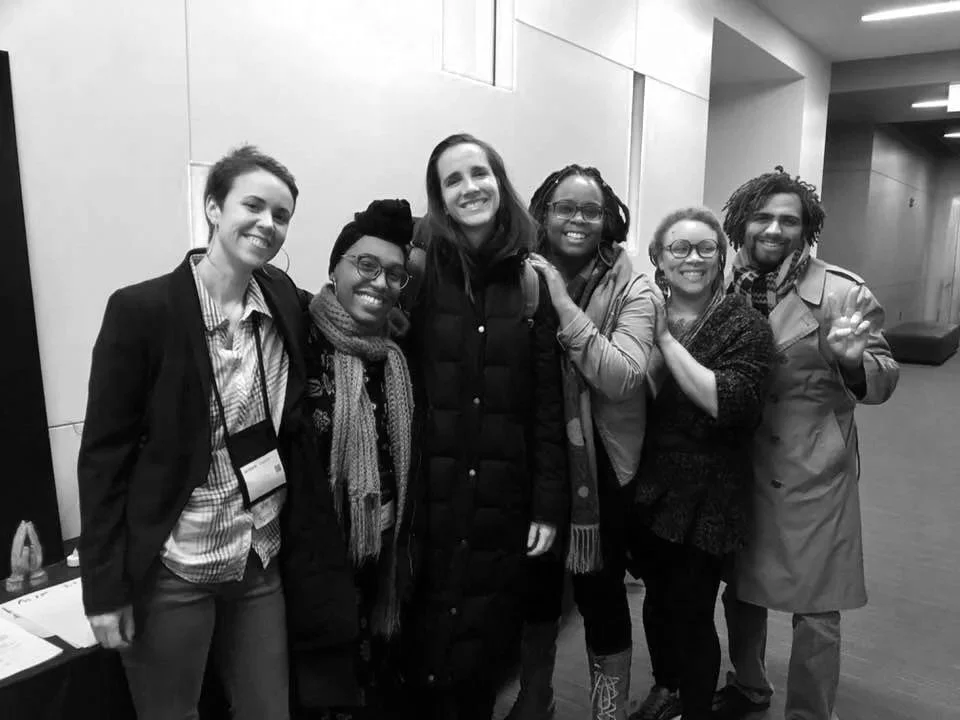 A group of six diverse people smiling and posing together indoors.