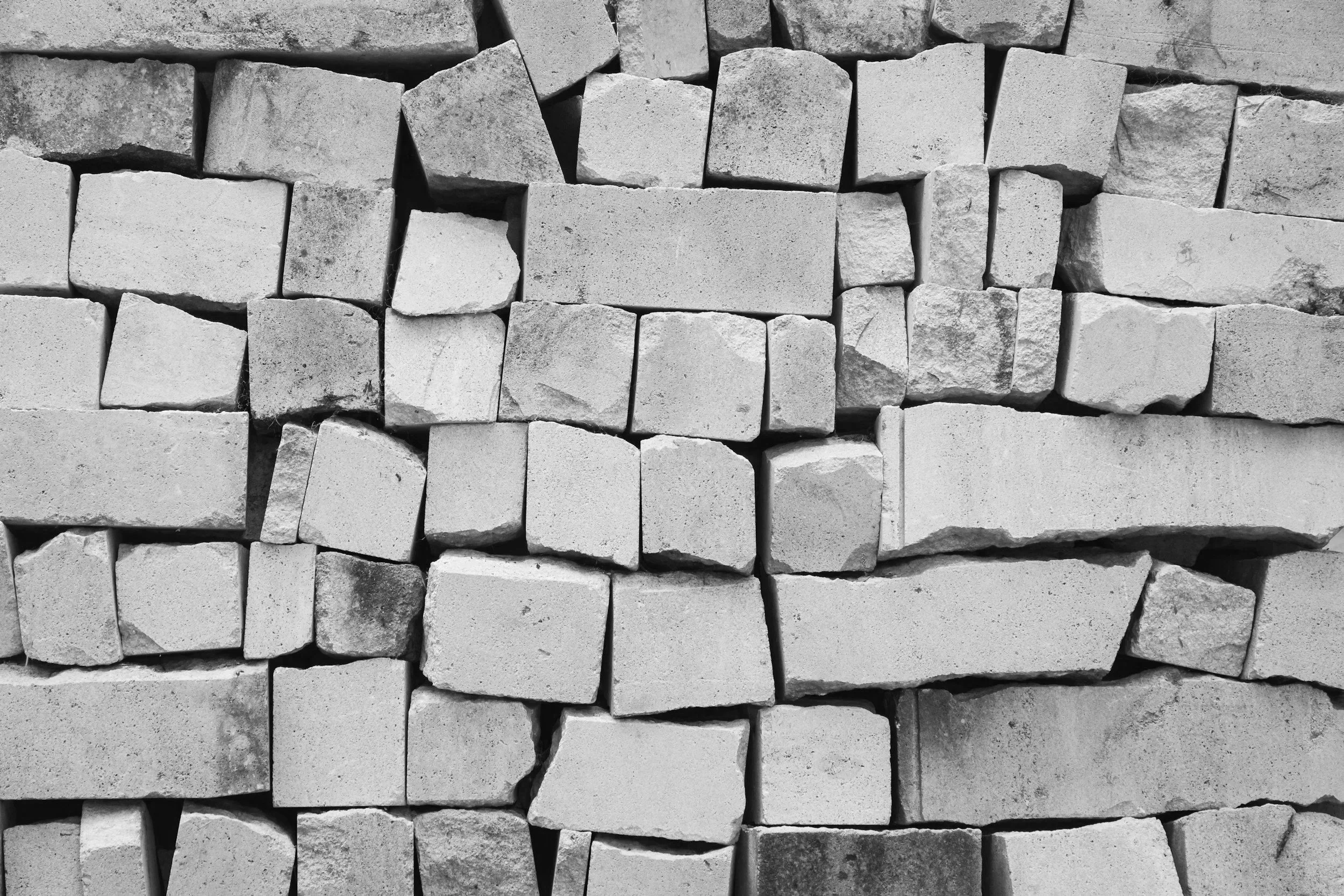 Stacked rectangular and irregularly shaped concrete blocks in black and white.