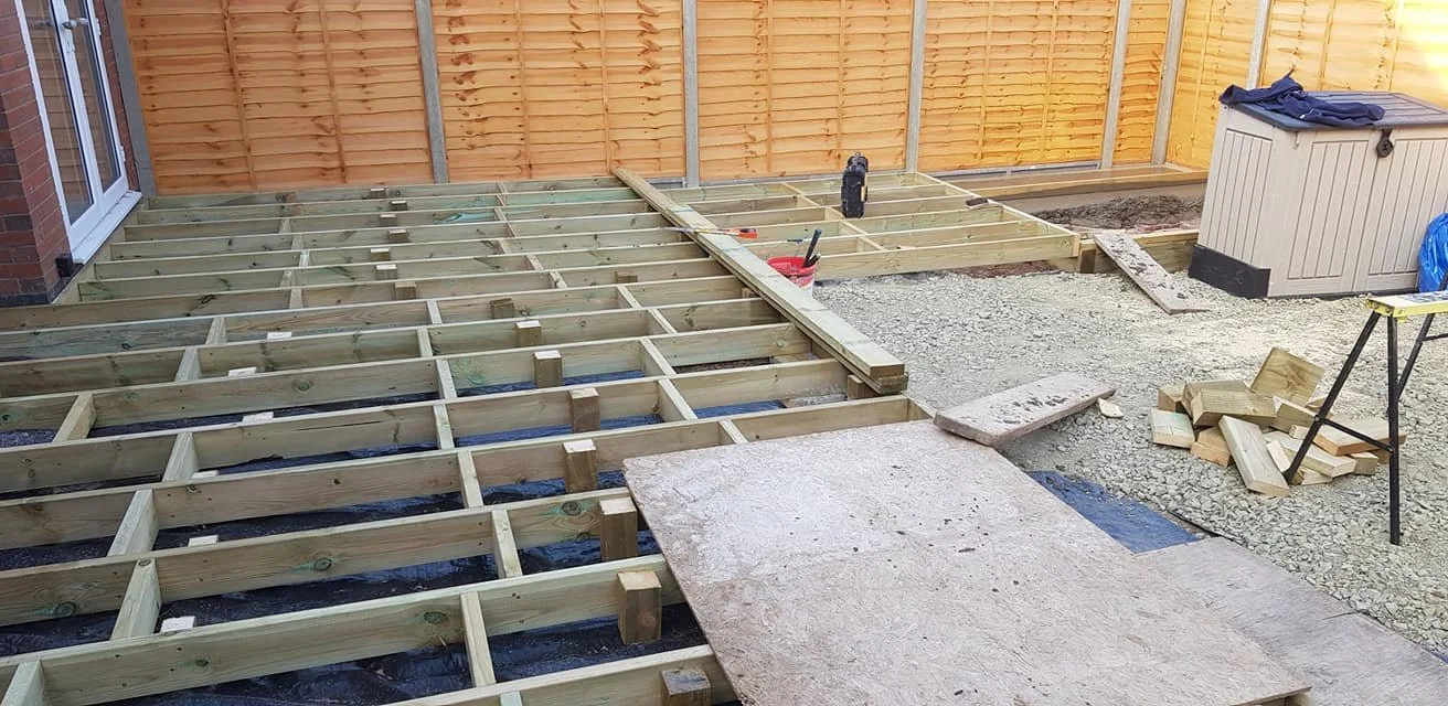  Backyard deck under construction with wooden framing, construction tools, and materials.