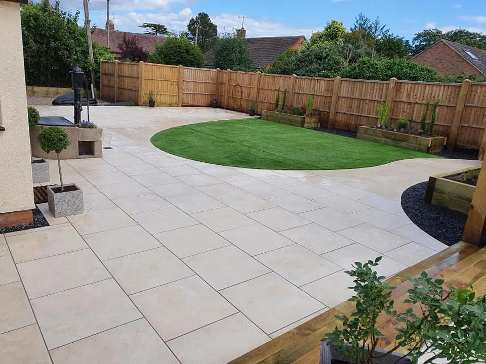 Backyard with patio, artificial grass patch, wooden fence, potted plants, and outdoor furniture.