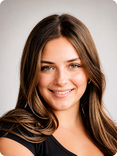 Close-up portrait of a young woman with long brown hair, smiling, wearing a black top against a neutral background.