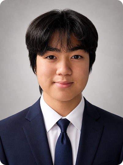 Young man in a navy suit and tie smiling at the camera against a gray background.