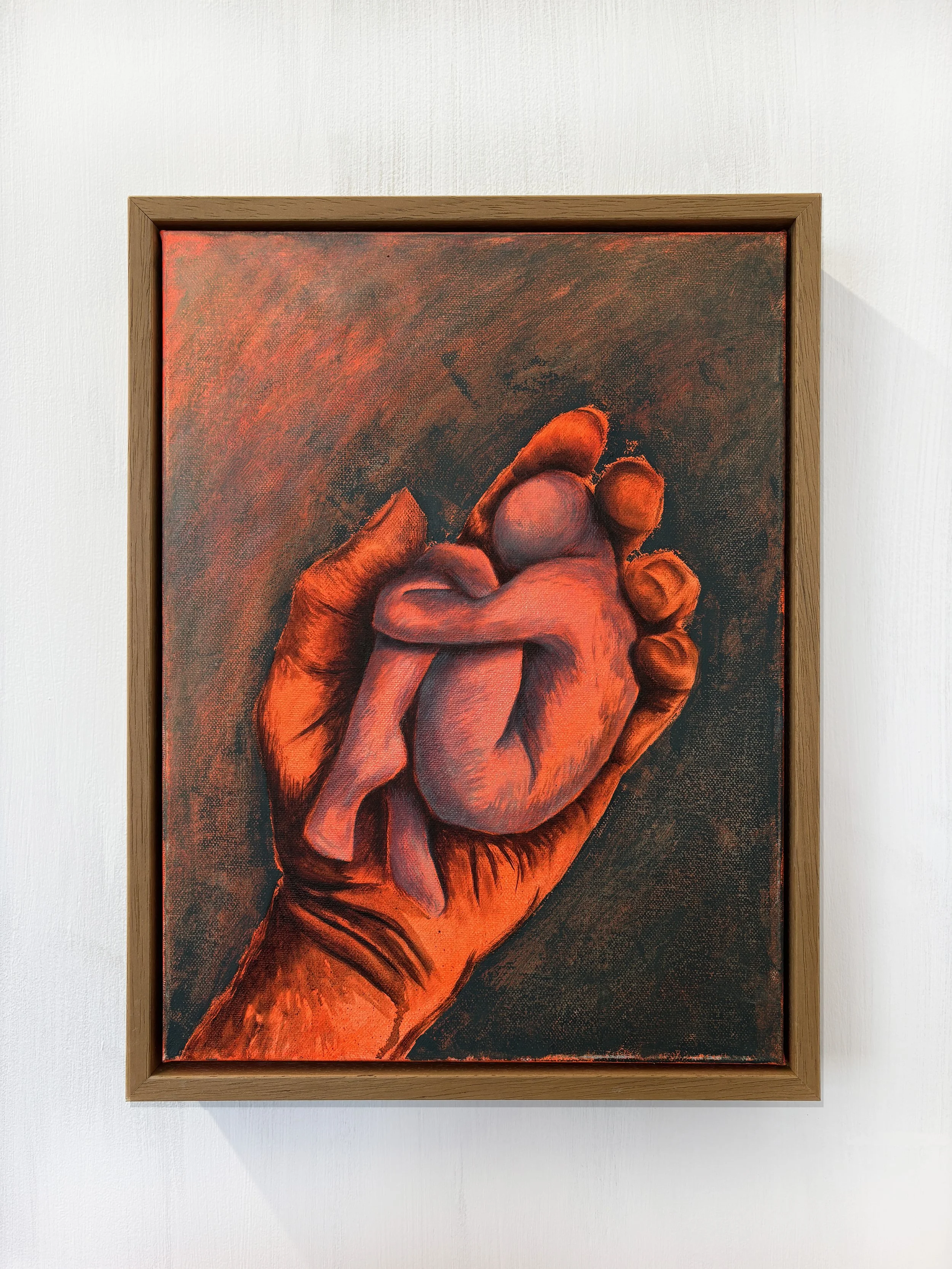 Painting of a hand holding a realistic human heart, framed and hanging on a white wall.