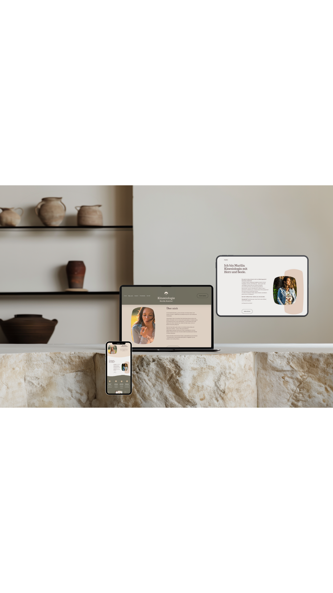 Bild zeigt drei digitale Geräte (Smartphone, Laptop, Tablet) mit einer Website über Kinesiologie, auf einer Steinoberfläche, im Hintergrund eine Wand mit aufgestellten Keramikgefäßen.