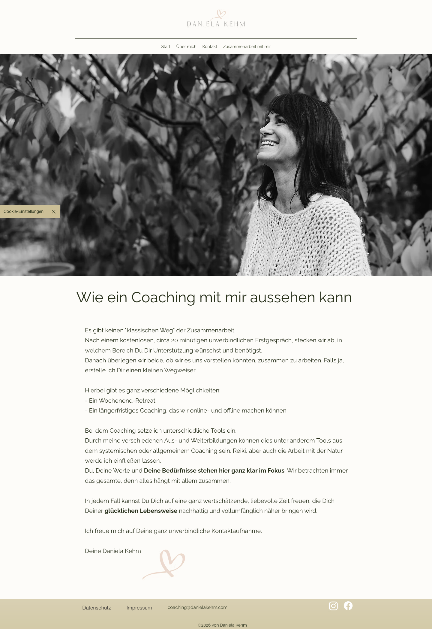 Schwarz-weiß-Bild einer lächelnden Frau mit dunklem Haar, die vor einem Baum steht.