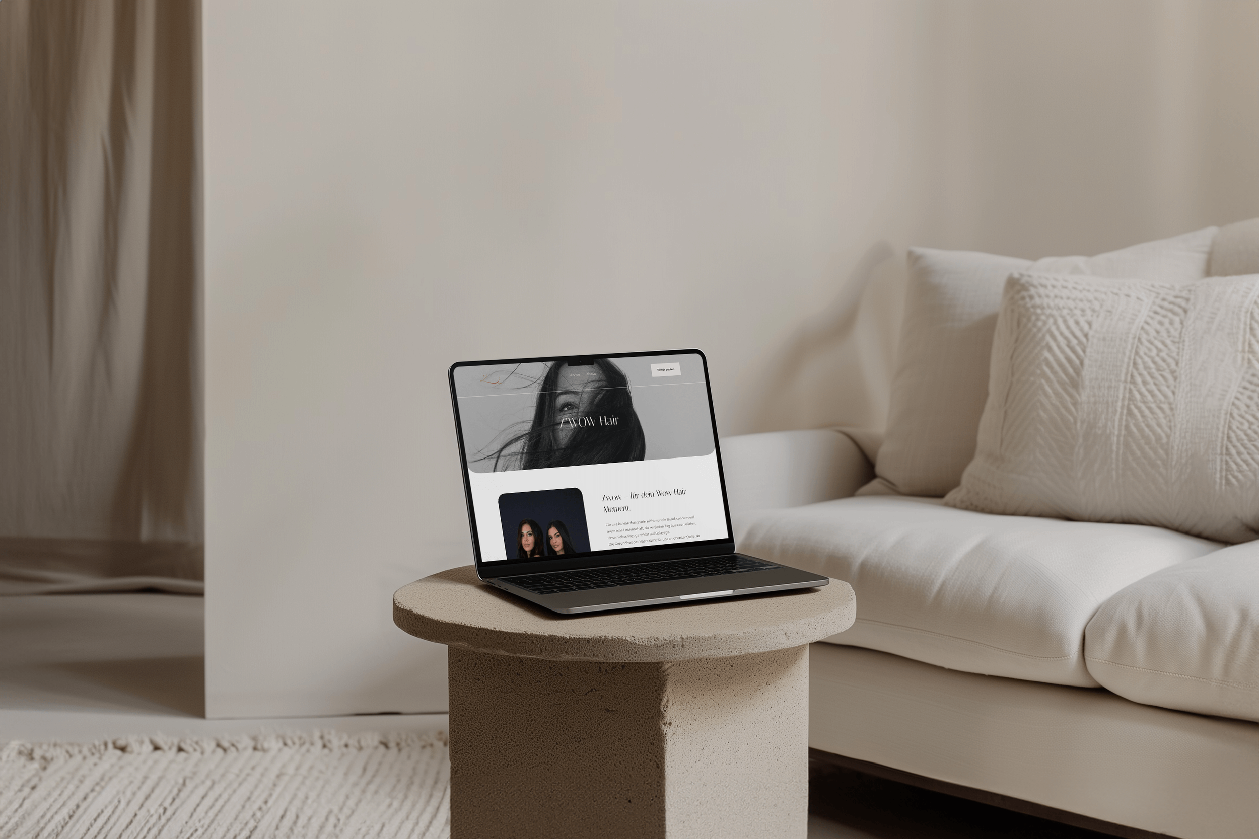 Laptop auf einem beigefarbenen Beistelltisch in einem Wohnzimmer mit weißem Sofa und Kissen, Bild zeigt eine Webseite für Wow Hair.