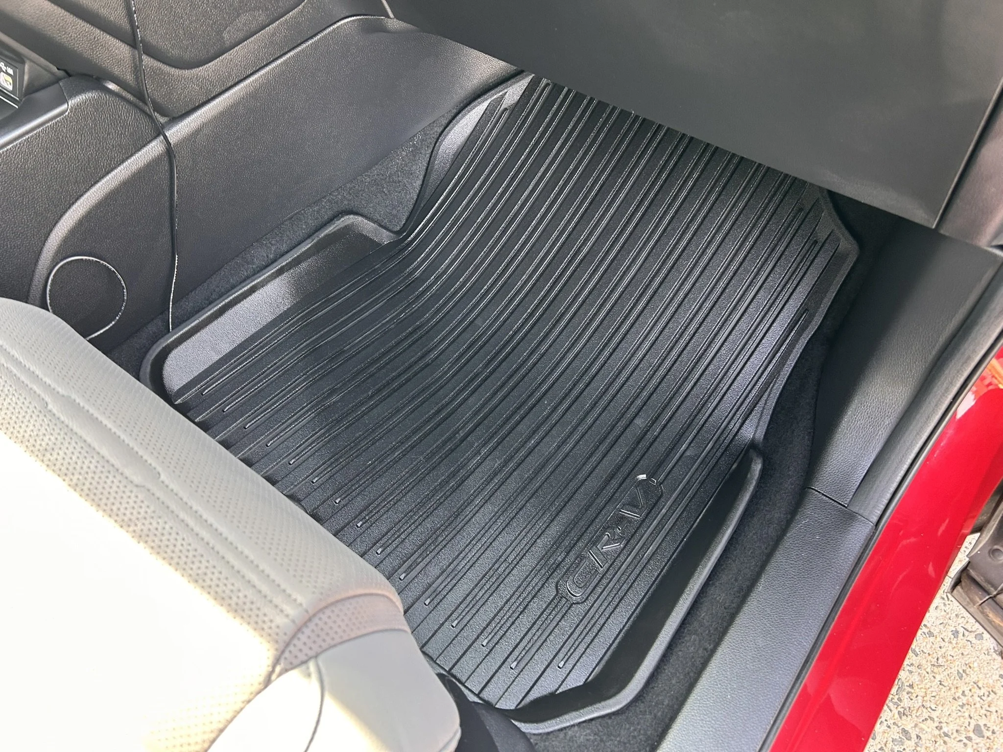 The front passenger side floor of a vehicle with a black rubber floor mat labeled 'Civic', and part of a beige seat in the foreground.