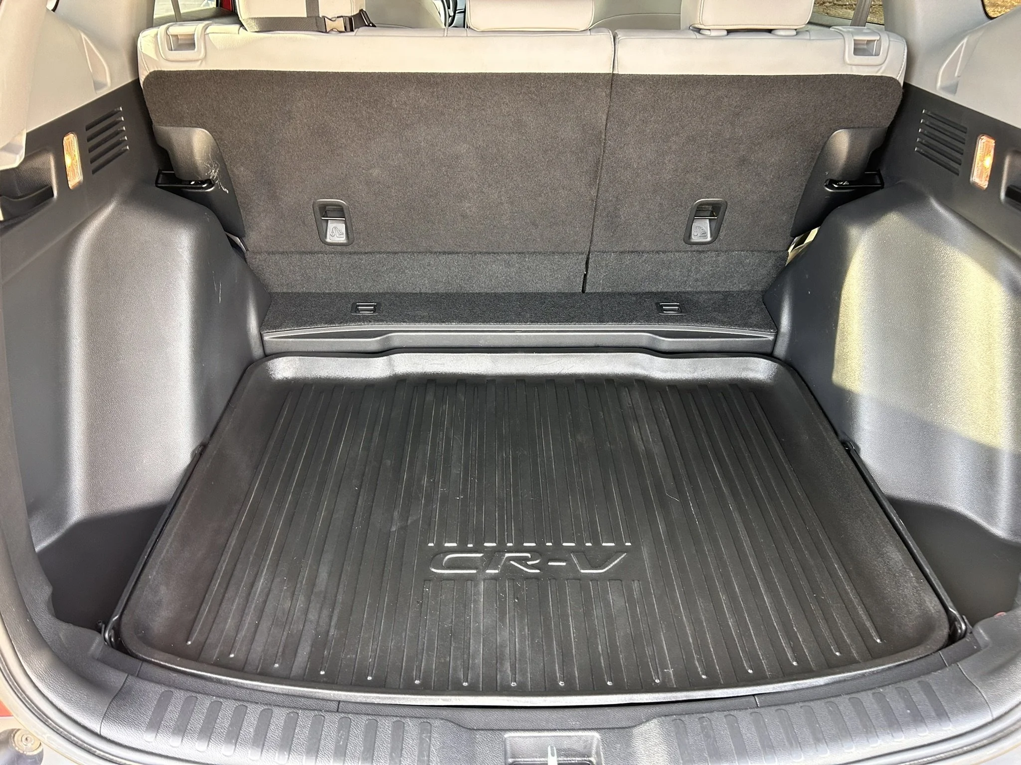 The empty trunk of a Honda CR-V SUV with a rubber cargo mat on the floor.