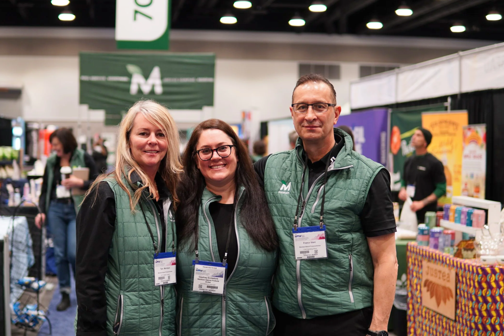 three people posing together and smiling at a convention