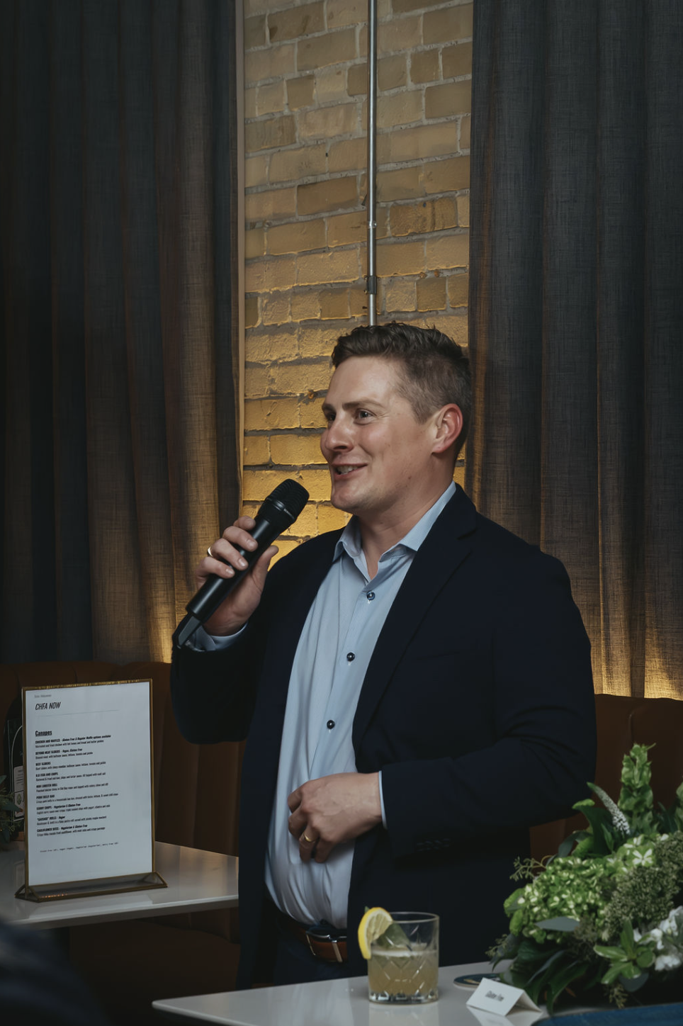 a man wearing a suit and talking into a microphone