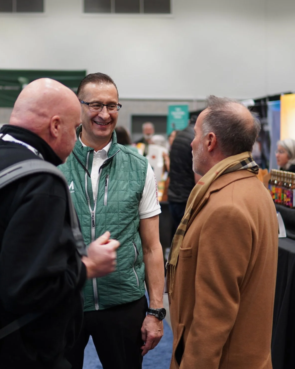 a small group of men smiling and talking at a convention