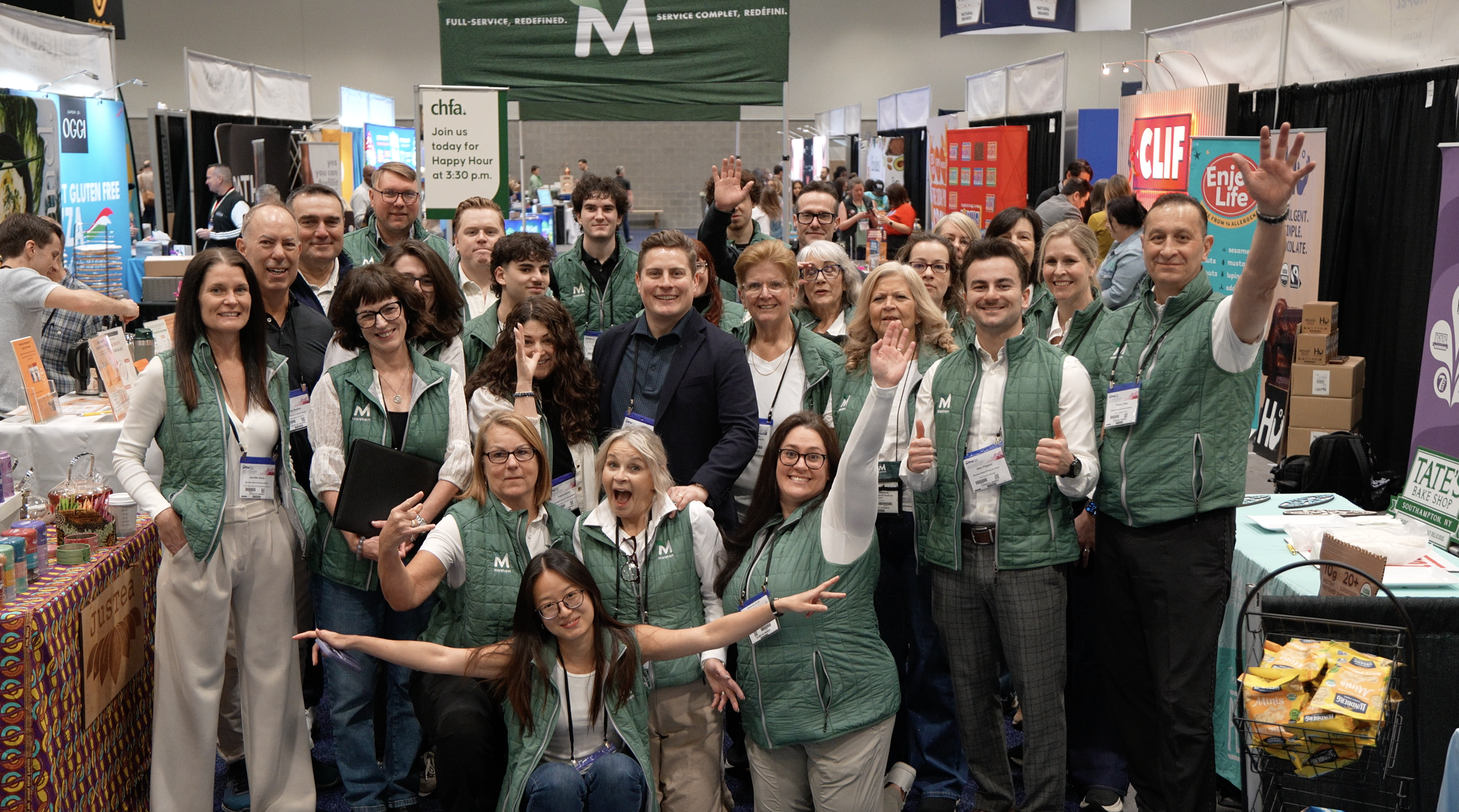 a large group of the Marsham team smiling and waving at the camera at a convention