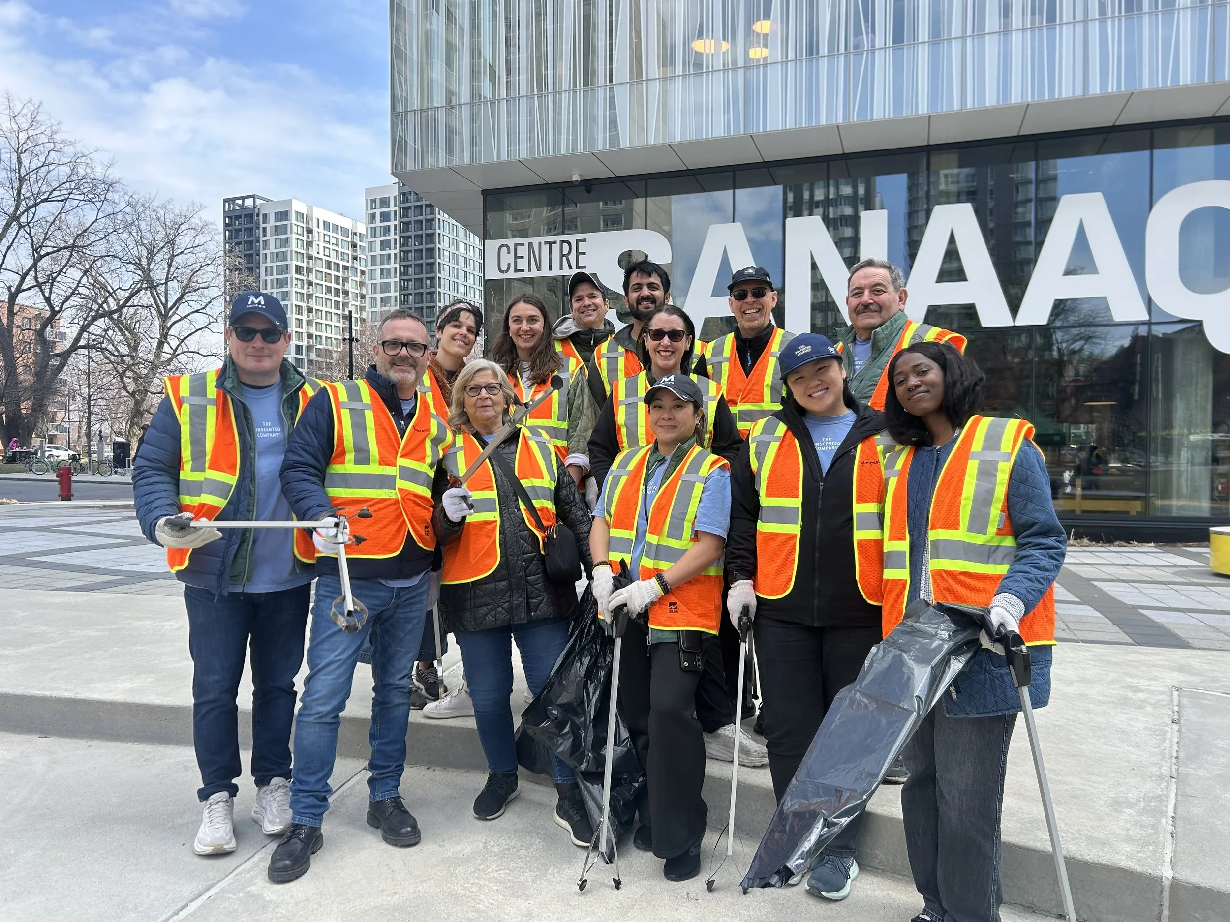 a group of people outside of a building while wearing neon vests and posing smiling for a photo