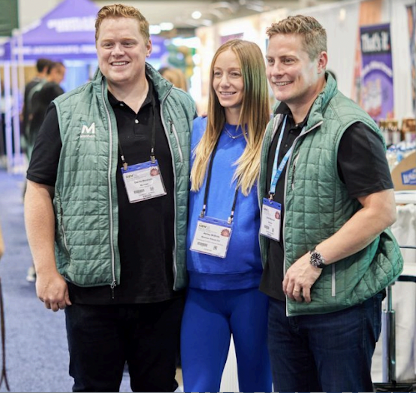 three people smiling and posing together for a photo at a convention