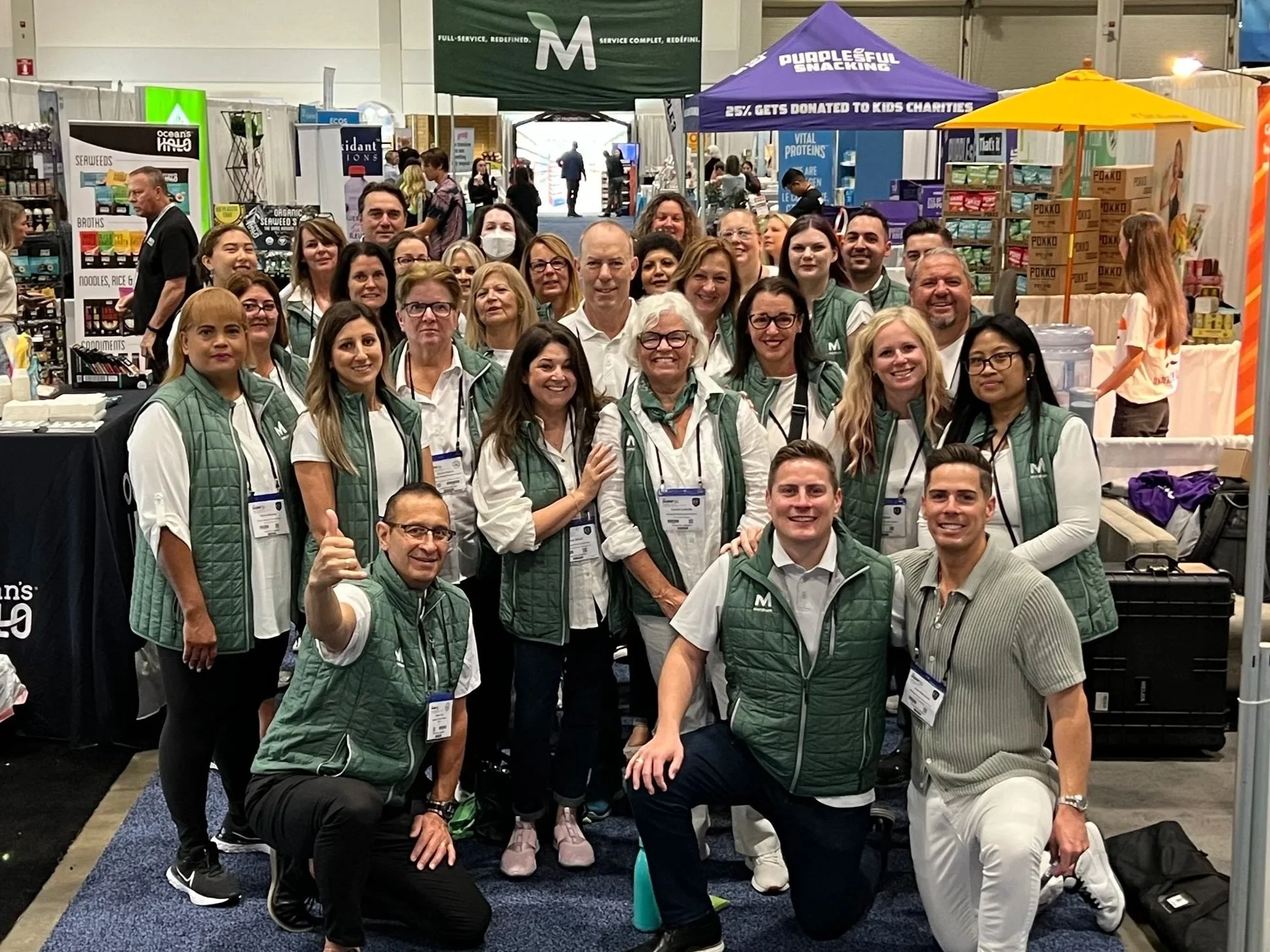 a large group of people smiling and posing for a photo at a convention