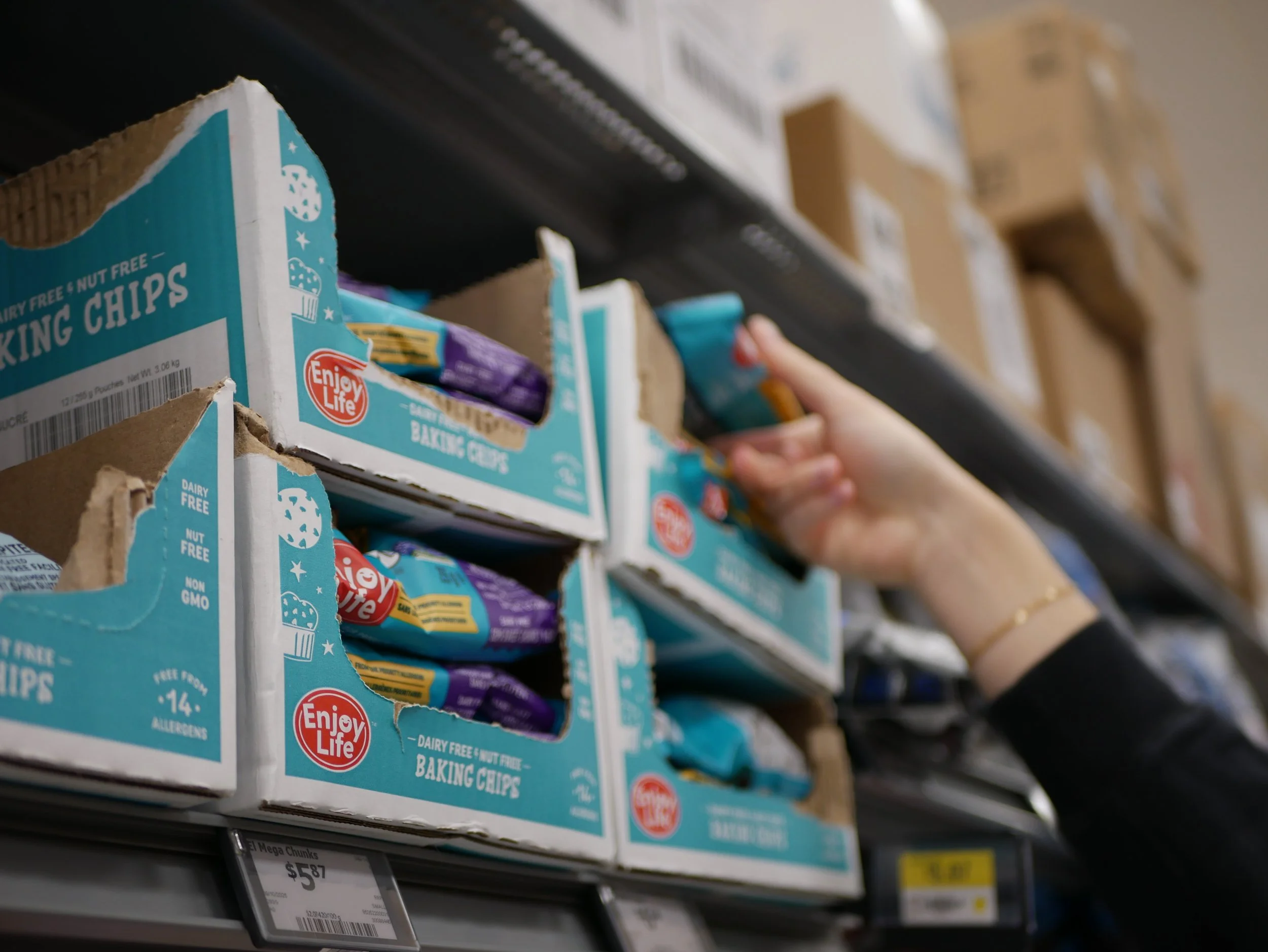 a hand reaching for Enjoy Life baking chips on a grocery store shelf