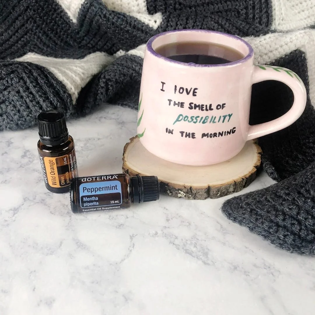 Tazza con scritta su base in legno e boccette di oli essenziali arancia e menta piperita