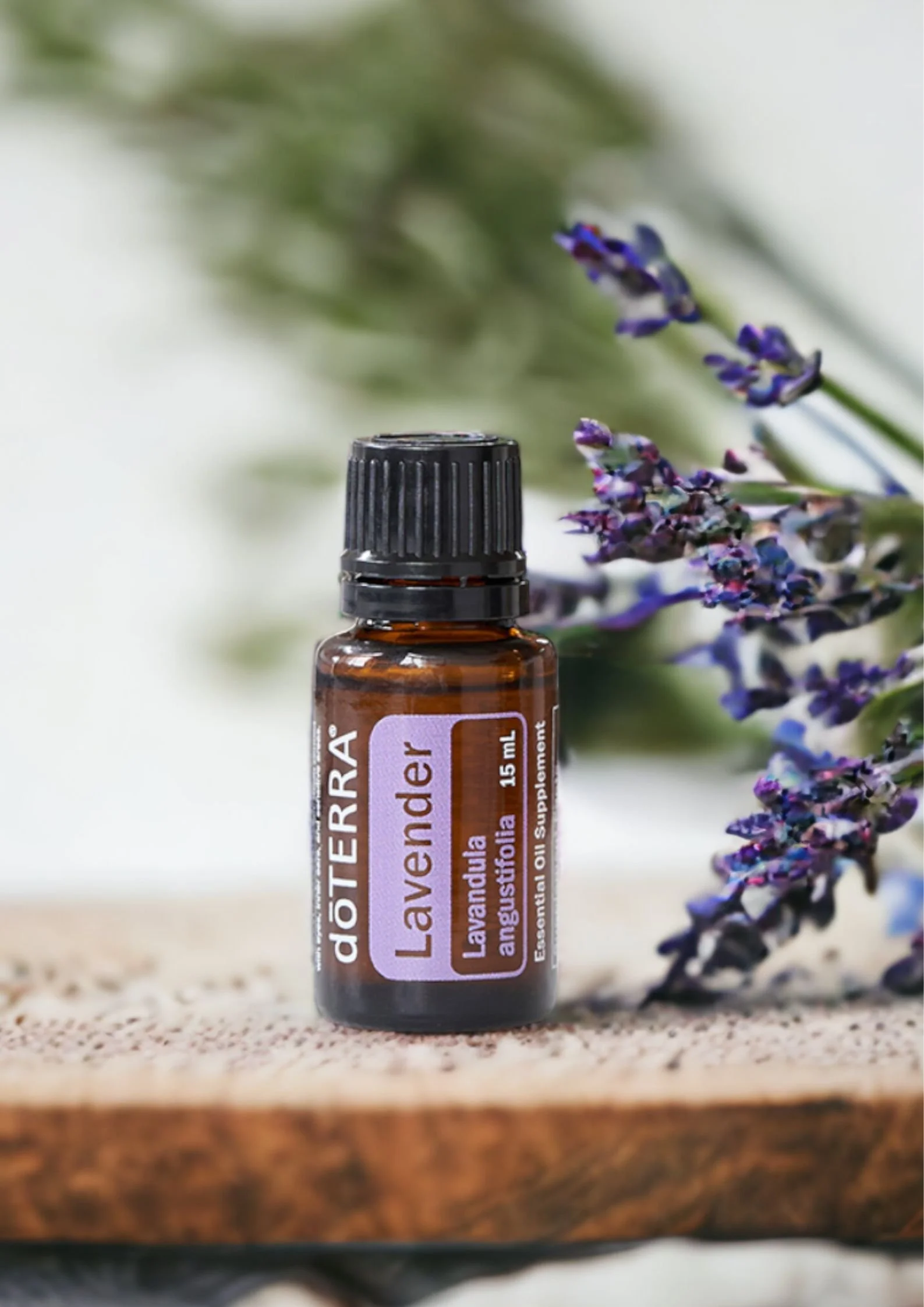 Boccetta di olio essenziale di Lavanda doTERRA su base di legno con fiori di lavanda vicino - Silvia Pagliarini