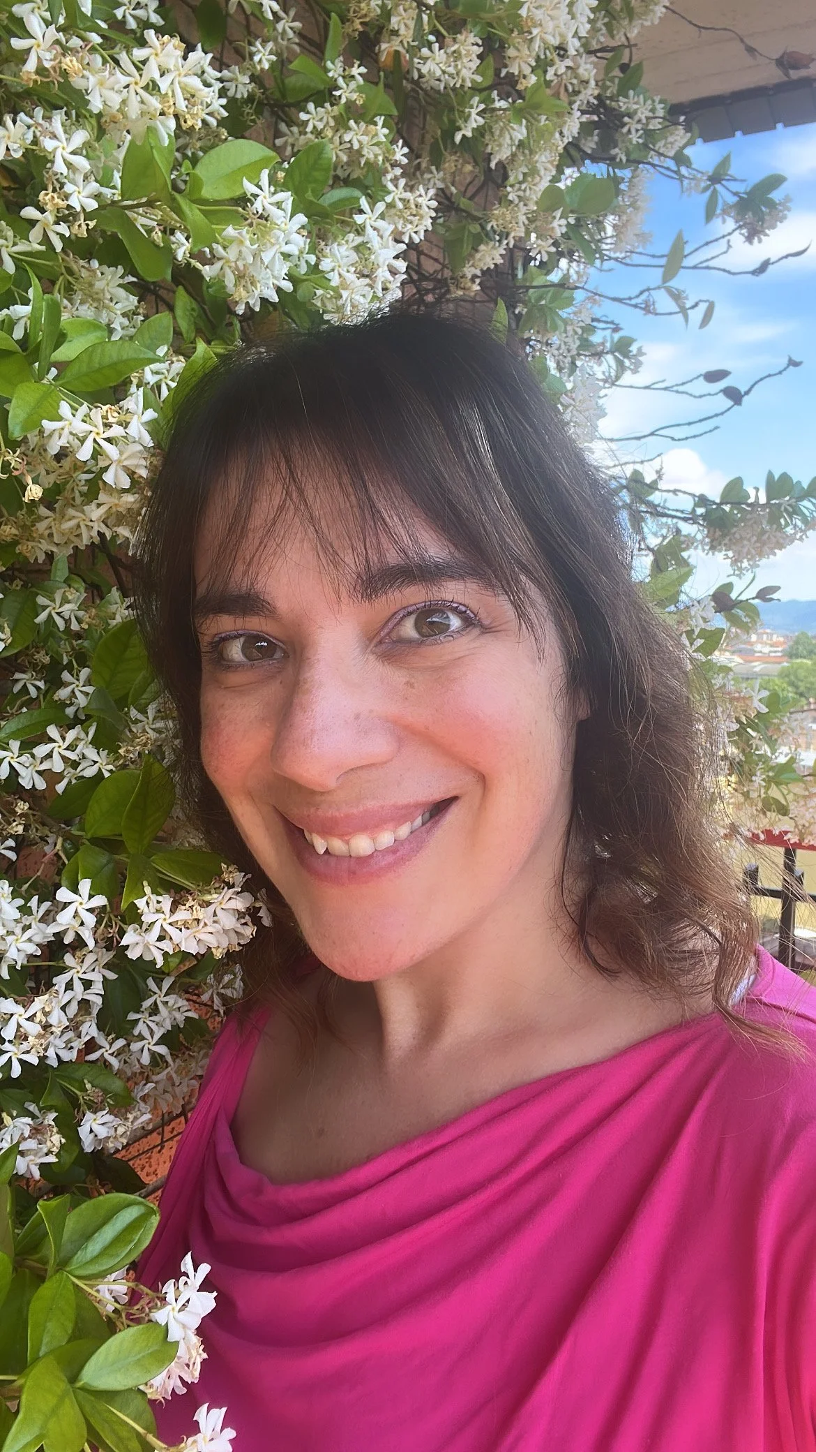 Silvia Pagliarini sorridente con tshirt fuxia vicino a una pianta di gelsomino