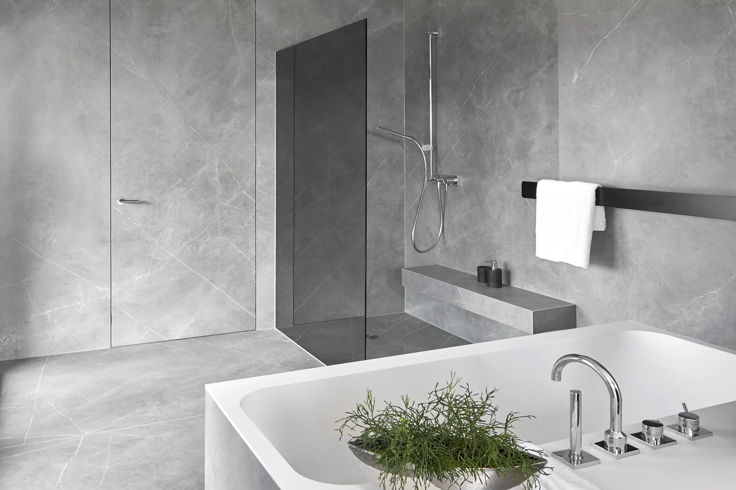 Modernes Badezimmer mit einer Badewanne, einer Dusche und grauen Marmormauern.
