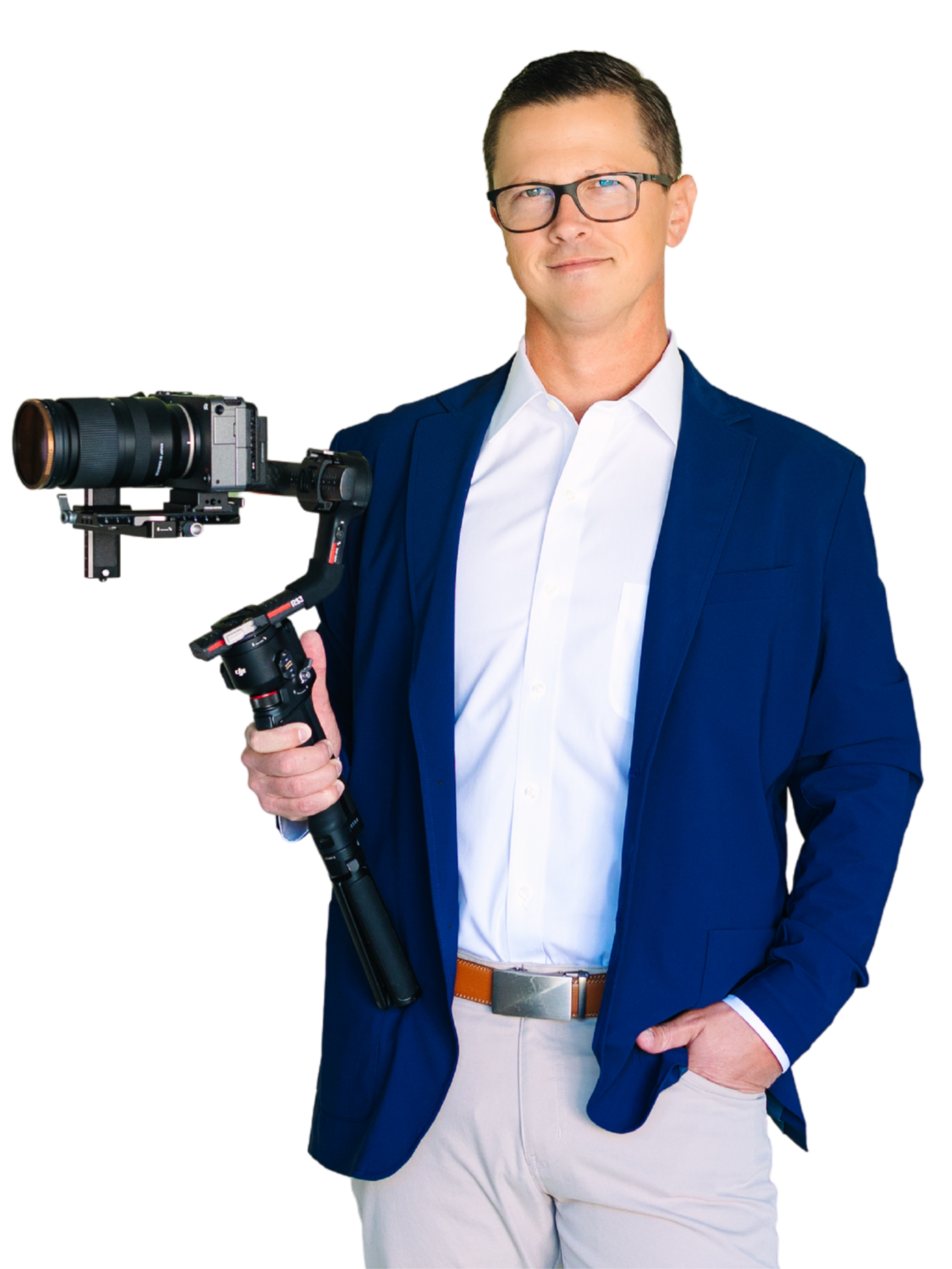 A man wearing glasses, a white shirt, a blue blazer, and beige pants holding a camera with a stabilizer.