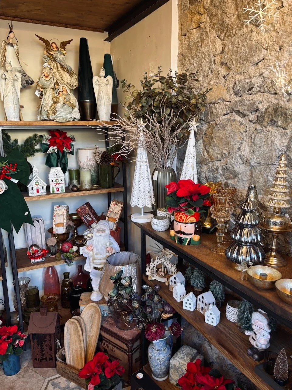Decorazioni natalizie con statuette di Babbo Natale, alberi di Natale, piante, luci e addobbi, in un negozio o casa.