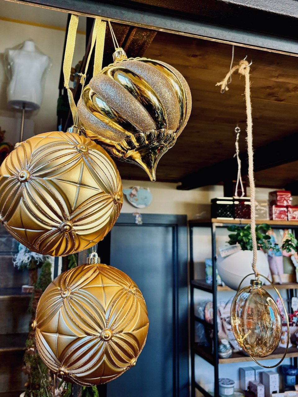 Decorazioni natalizie a forma di palline di vetro dorate e argentate appese al soffitto di un negozio.