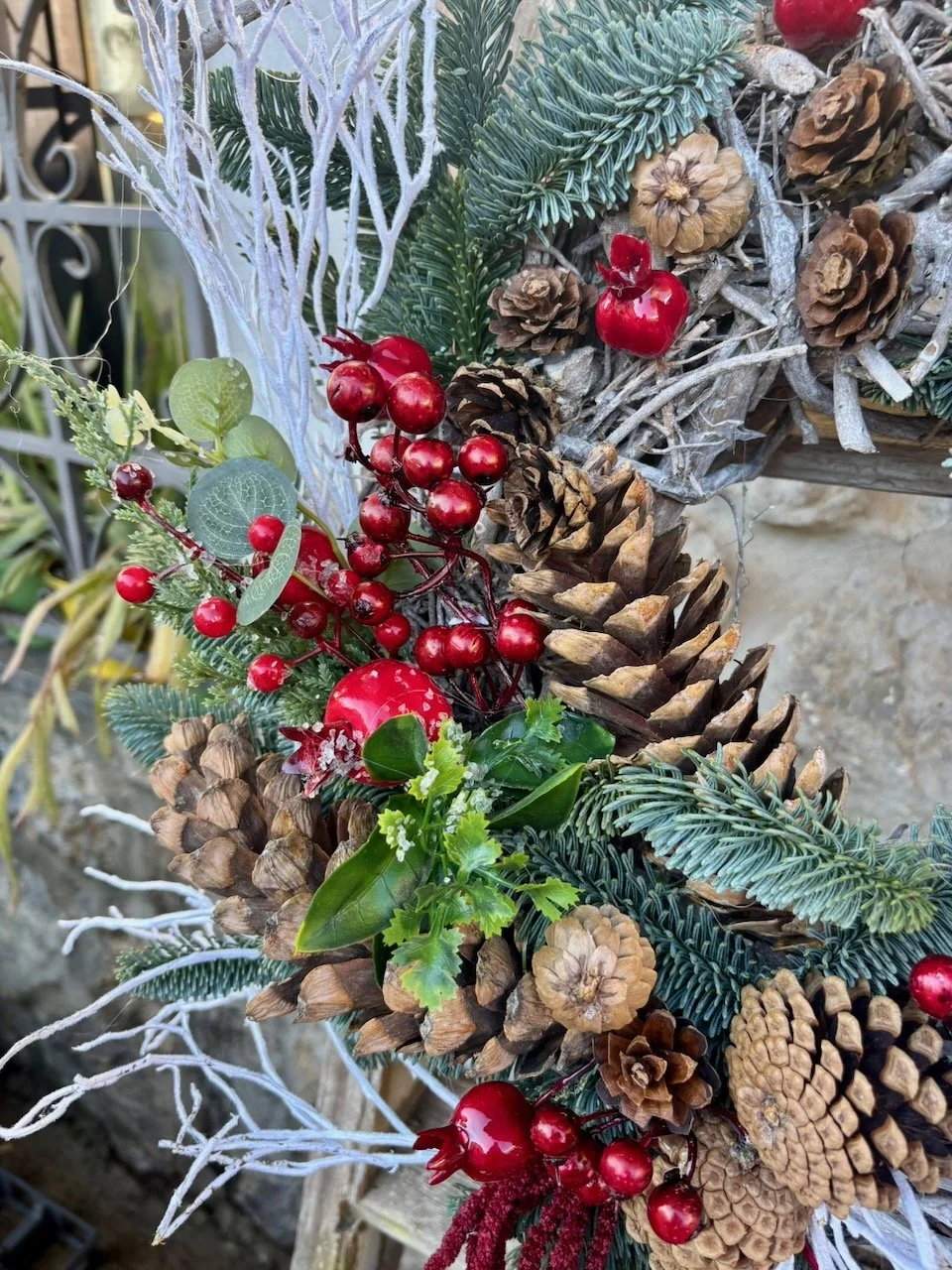 Decorazione natalizia con pigne, rami di abete, bacche rosse e ornamenti rossi.