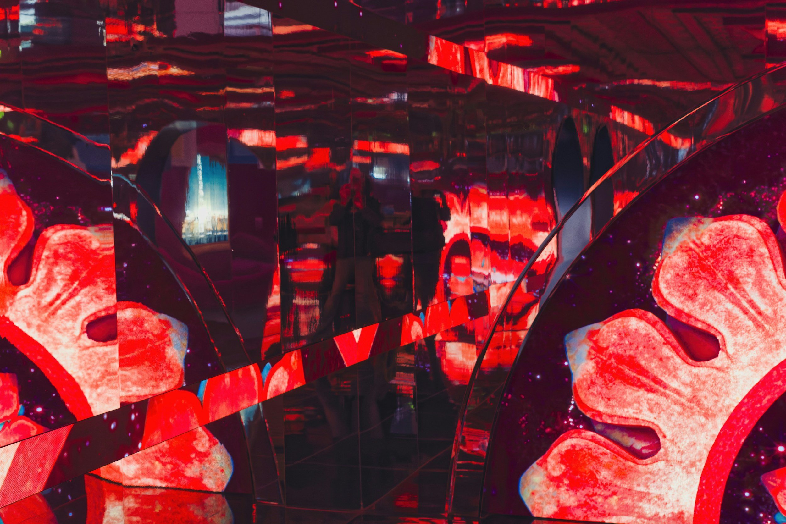 Colorful abstract art installation with red and black elements, reflective surfaces, and bright lighting.