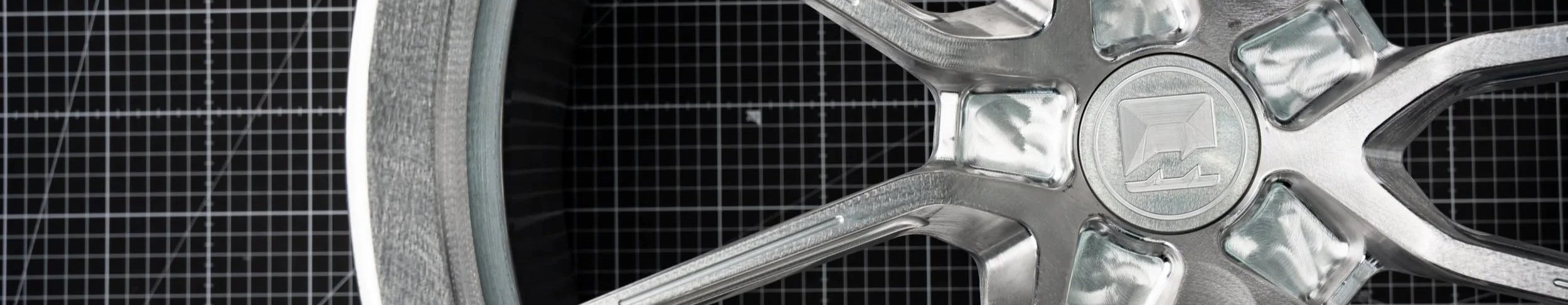 Close-up of a silver metal wheel rim against a black background with a grid pattern.