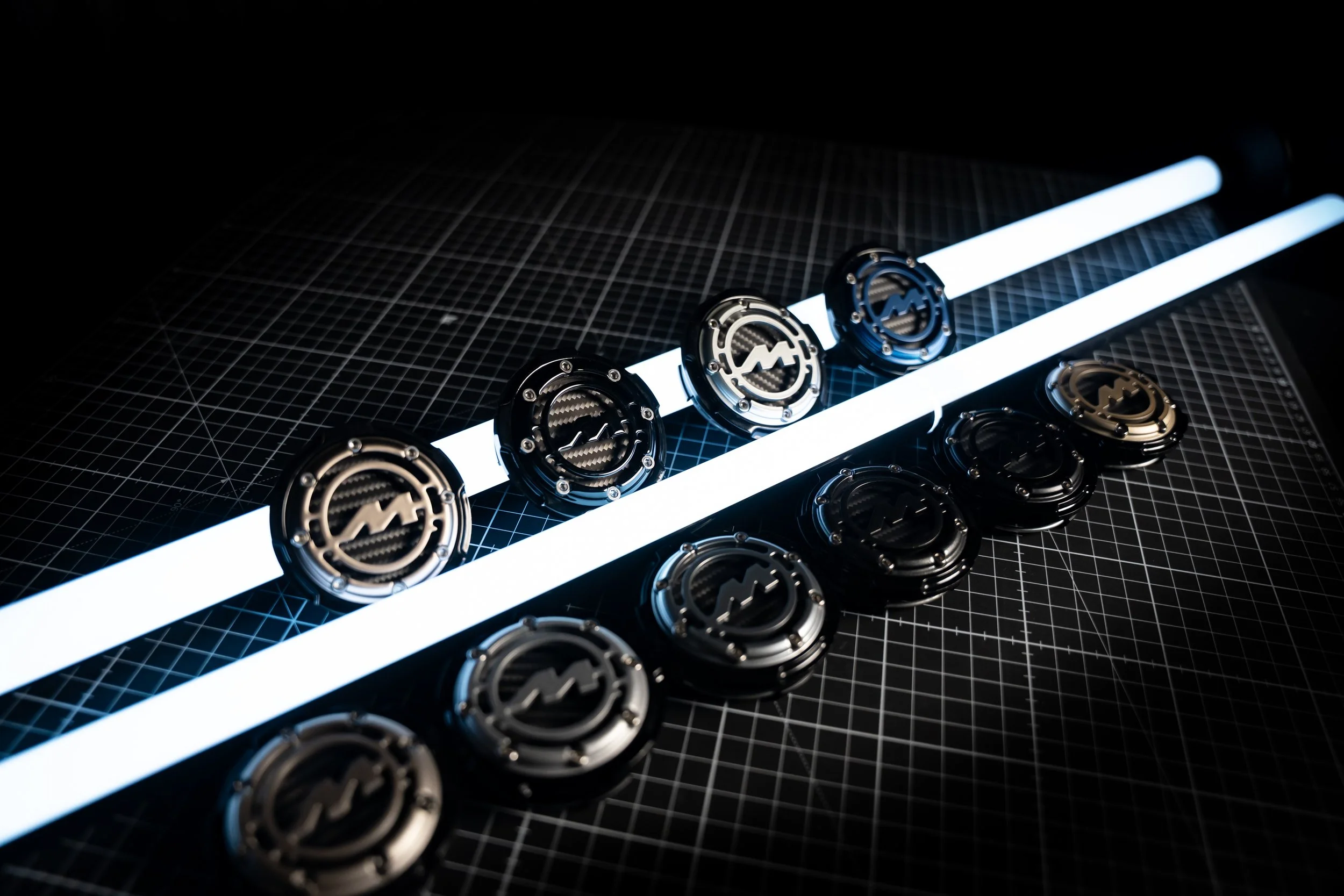 Multiple metallic cryptocurrency coins arranged on a black grid surface with two illuminated white lines in the background.