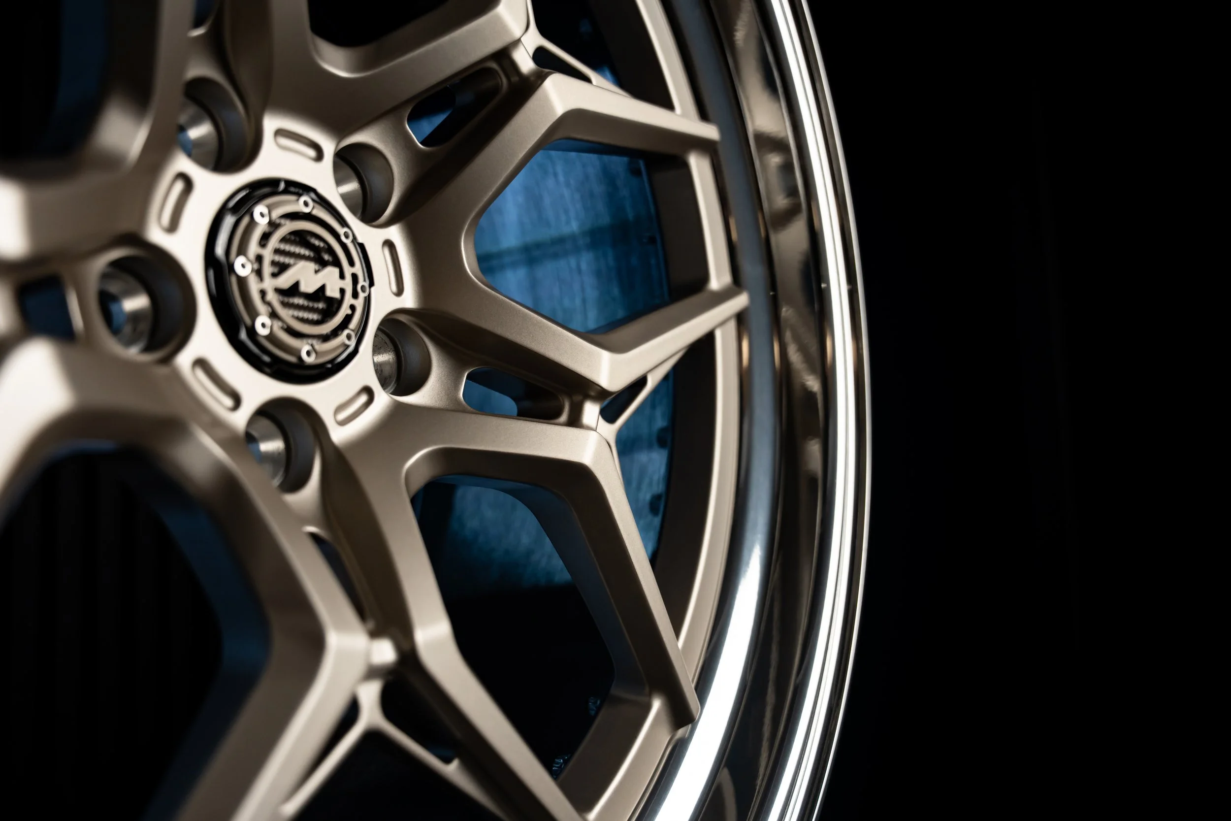 Close-up of a silver alloy wheel with a black center cap, set against a dark background.