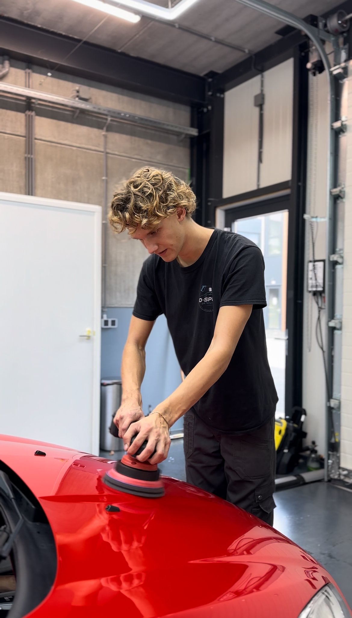 Een jongeman die bezig is met het polijsten van een exclusieve auto