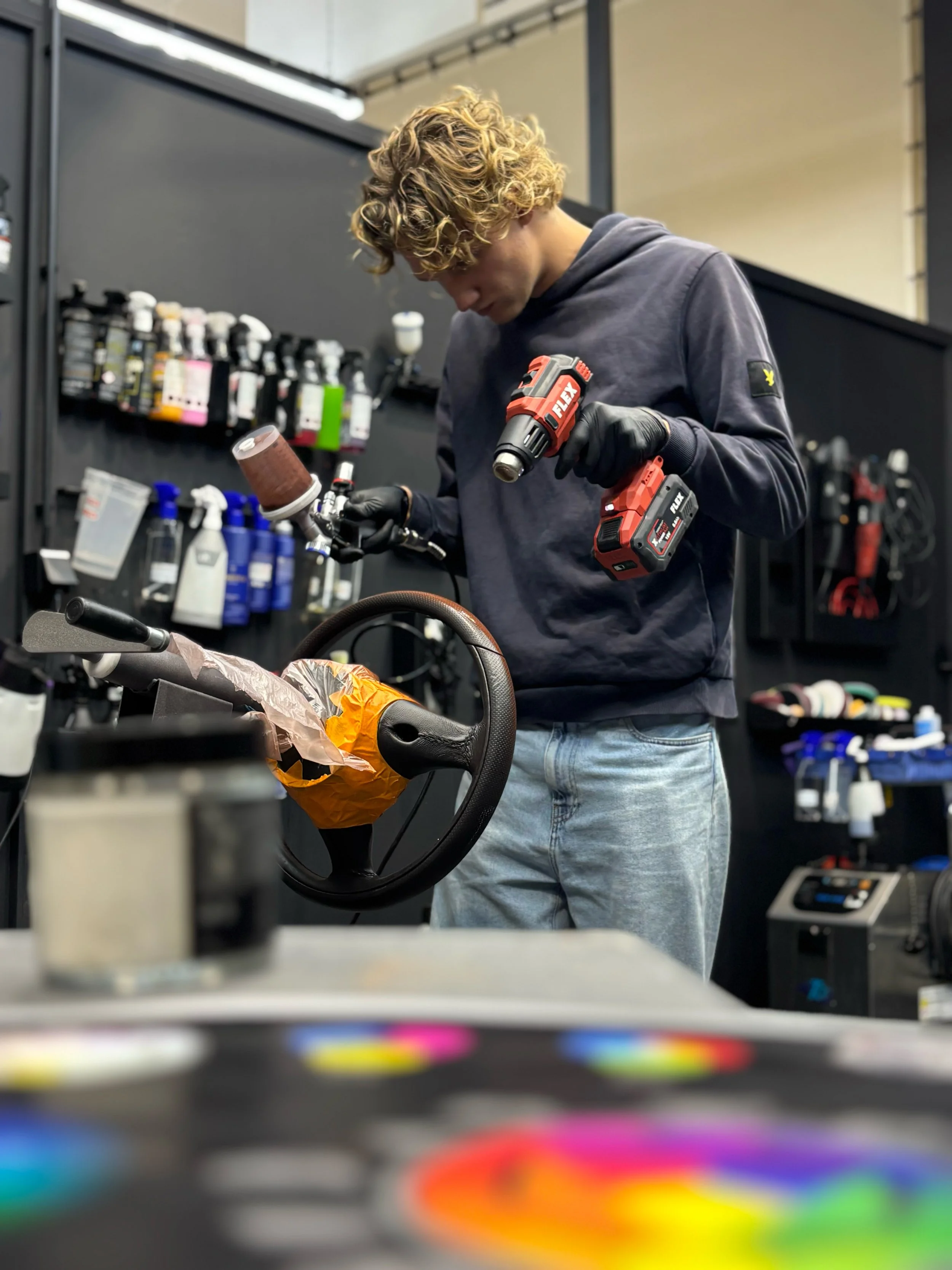 Een jonge man met krullend blond haar bezig met een lederen stuur die hij aan het herstellen is.
