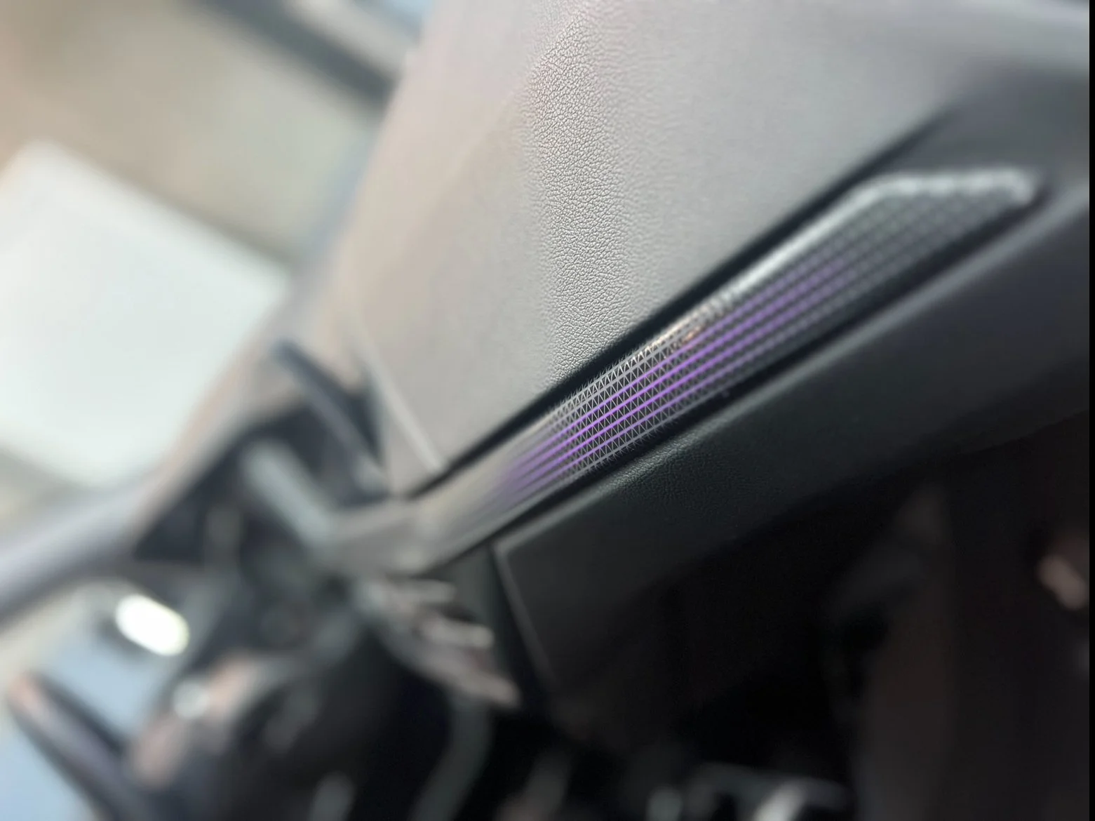 Close-up of a vehicle dashboard vent with purple accents.