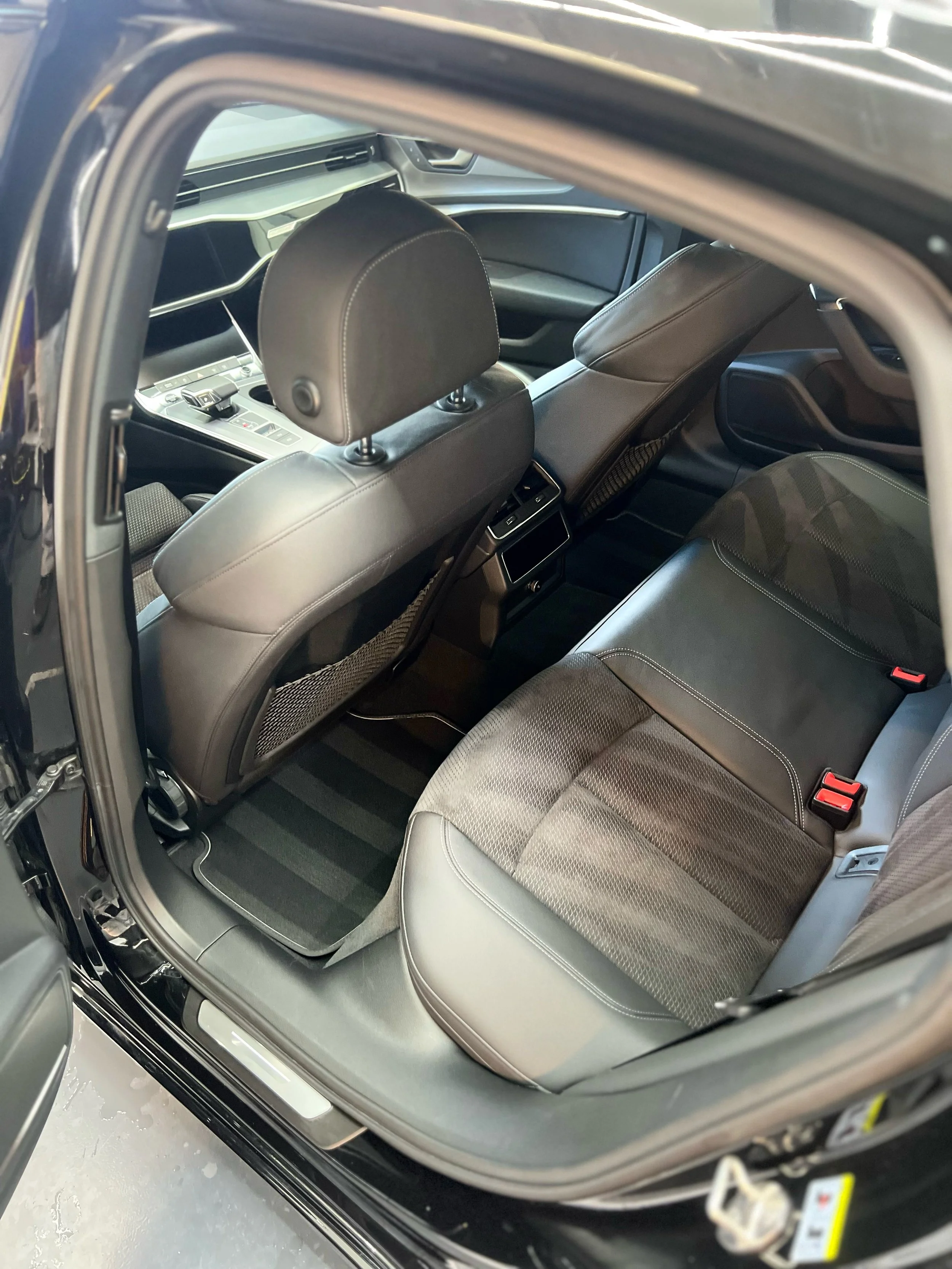 Interior view of a car showing the back seat, front seats, center console, and air vents.