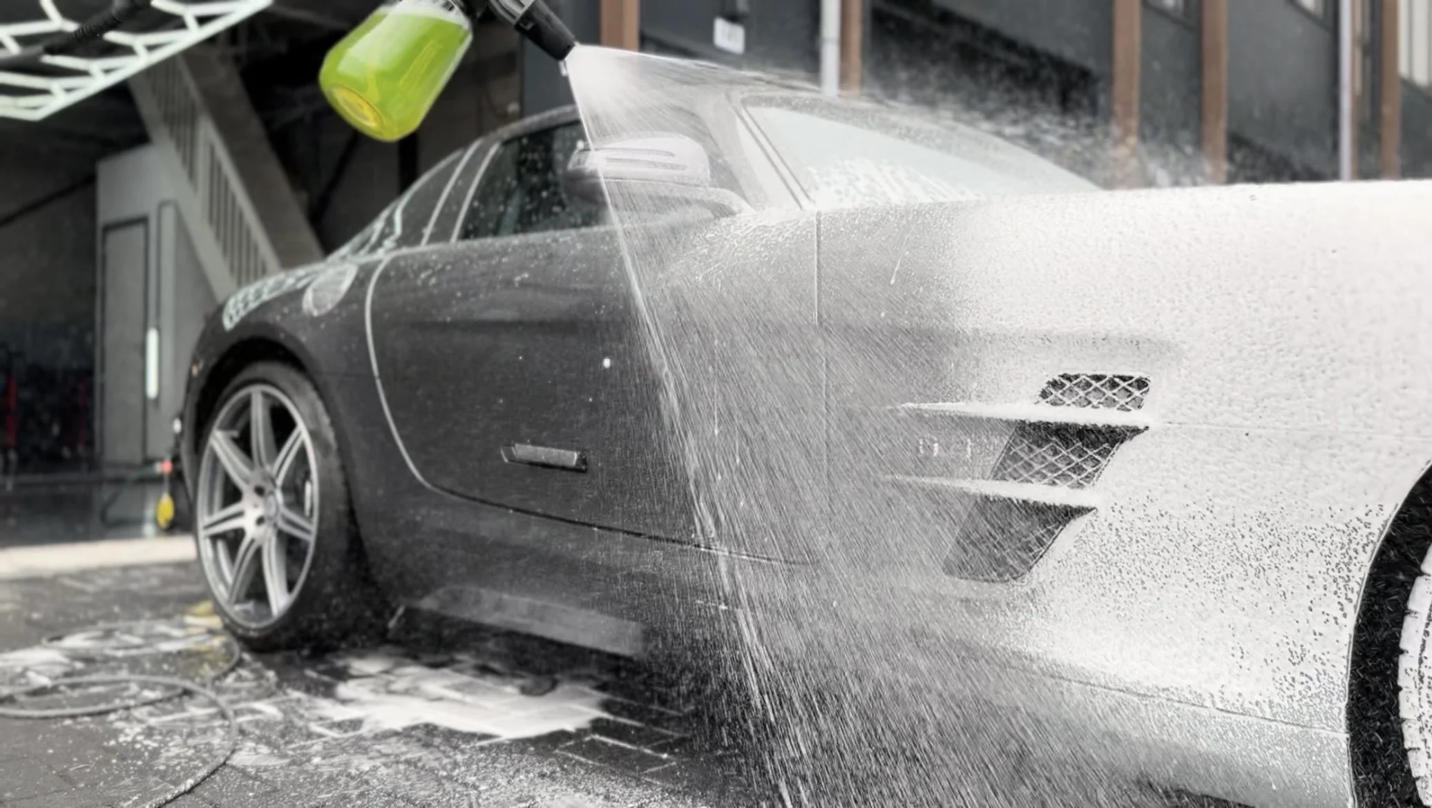 Een grijze Mercedes SLS die met een foamcannon wordt gedetaild.