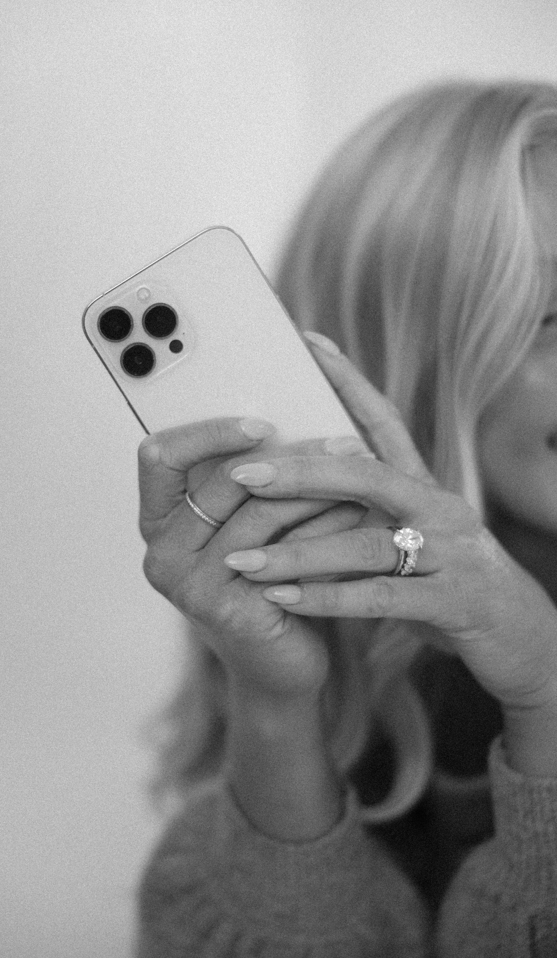 Black-and-white detail shot of a woman holding a smartphone, representing content creation, social media strategy, and digital presence consulting.