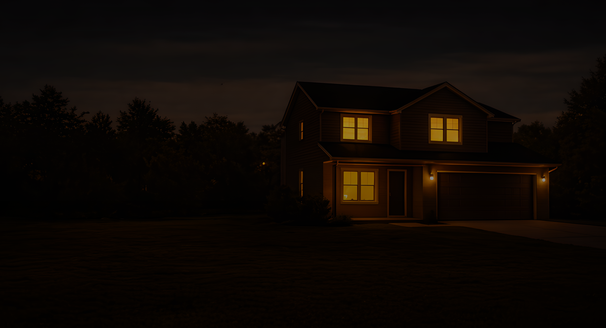 Ein zweistöckiges Haus mit eingeschalteten Lichtern bei Nacht, umgeben von Bäumen und einem dunklen Himmel.