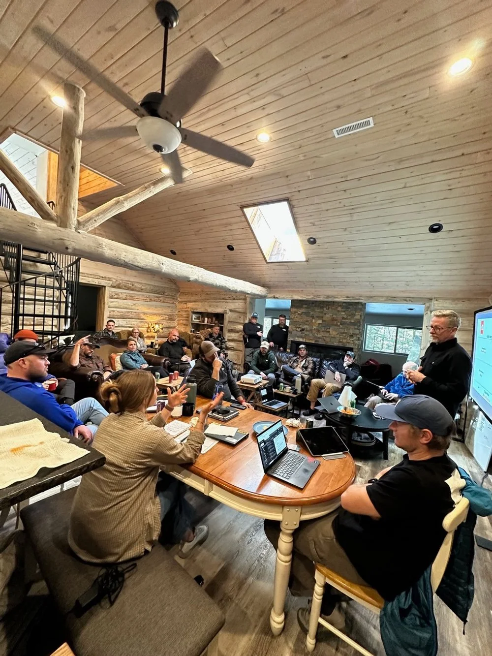 Group of people attending a meeting or workshop in a rustic, wood-paneled room