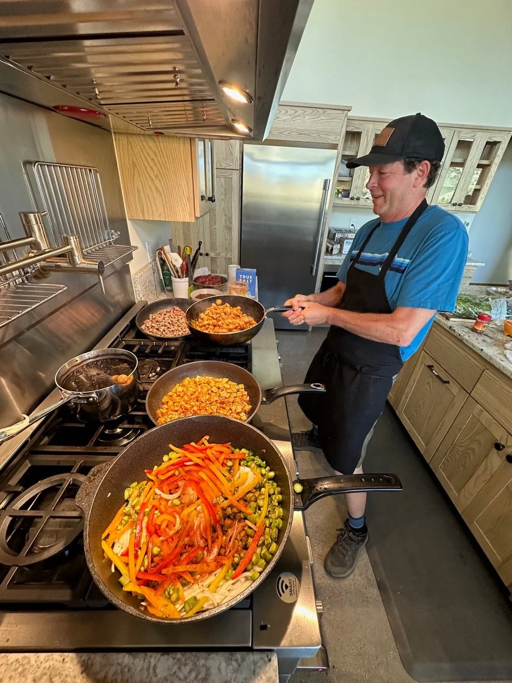 A man cooking multiple dishes on a stovetop in a kitchen