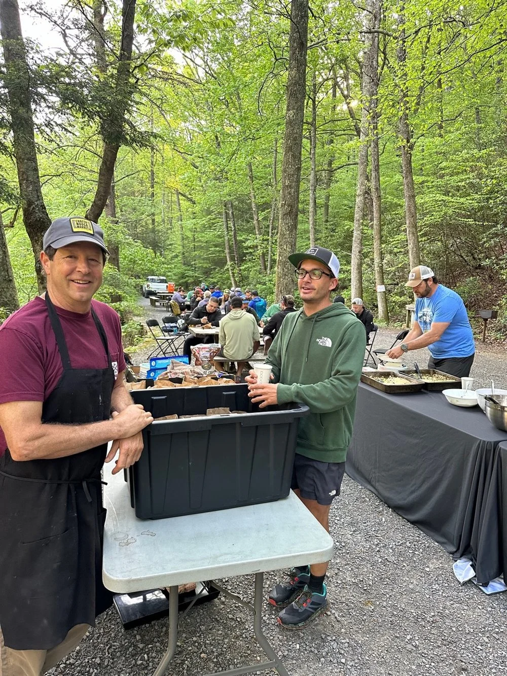 People at an outdoor gathering in a wooded area