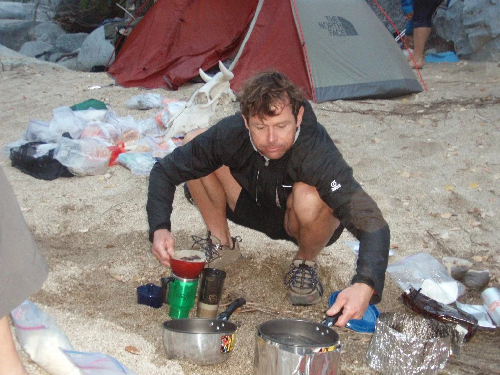 A man preparing food on the ground at a campsite