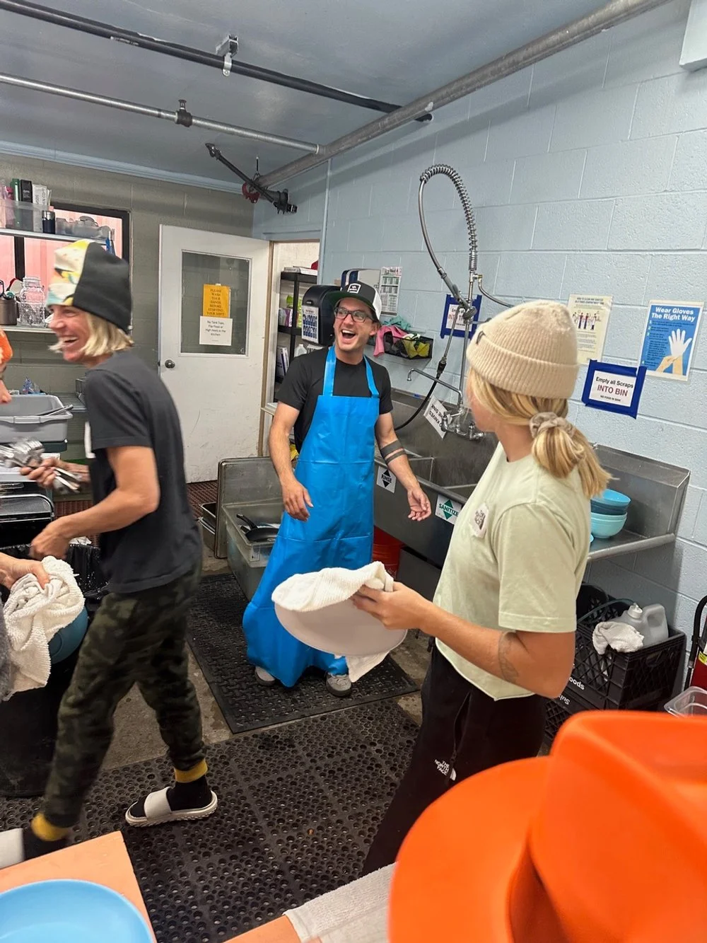 Three people working in a kitchen, laughing and smiling