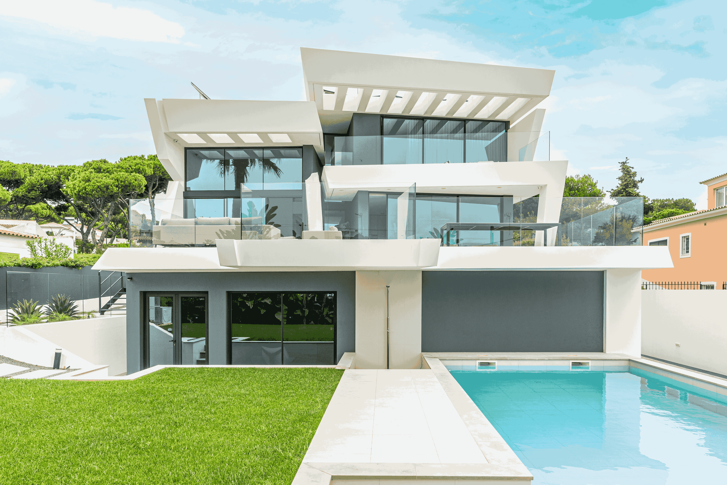Residência moderna com várias plataformas e janelas de vidro, piscina na frente e jardins bem cuidados ao redor.
