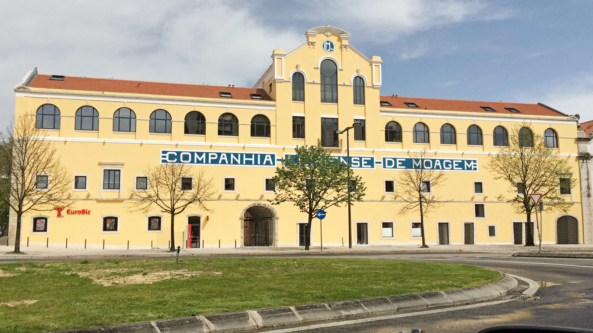 Prédio amarelado com janelas em arco e texto em destaque: 'Companhia de Moagem de Moagem'.