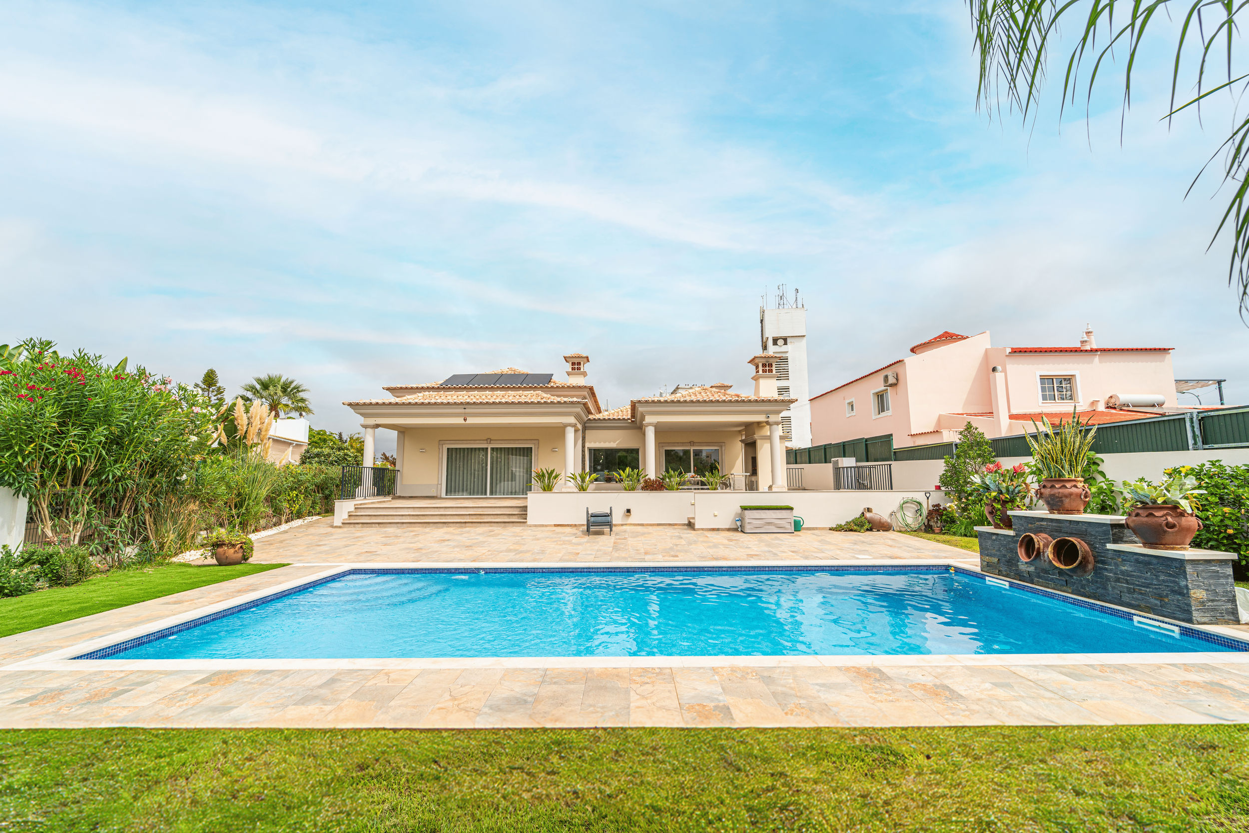 Casa com piscina ao ar livre, jardim bem cuidado e móveis de exterior.