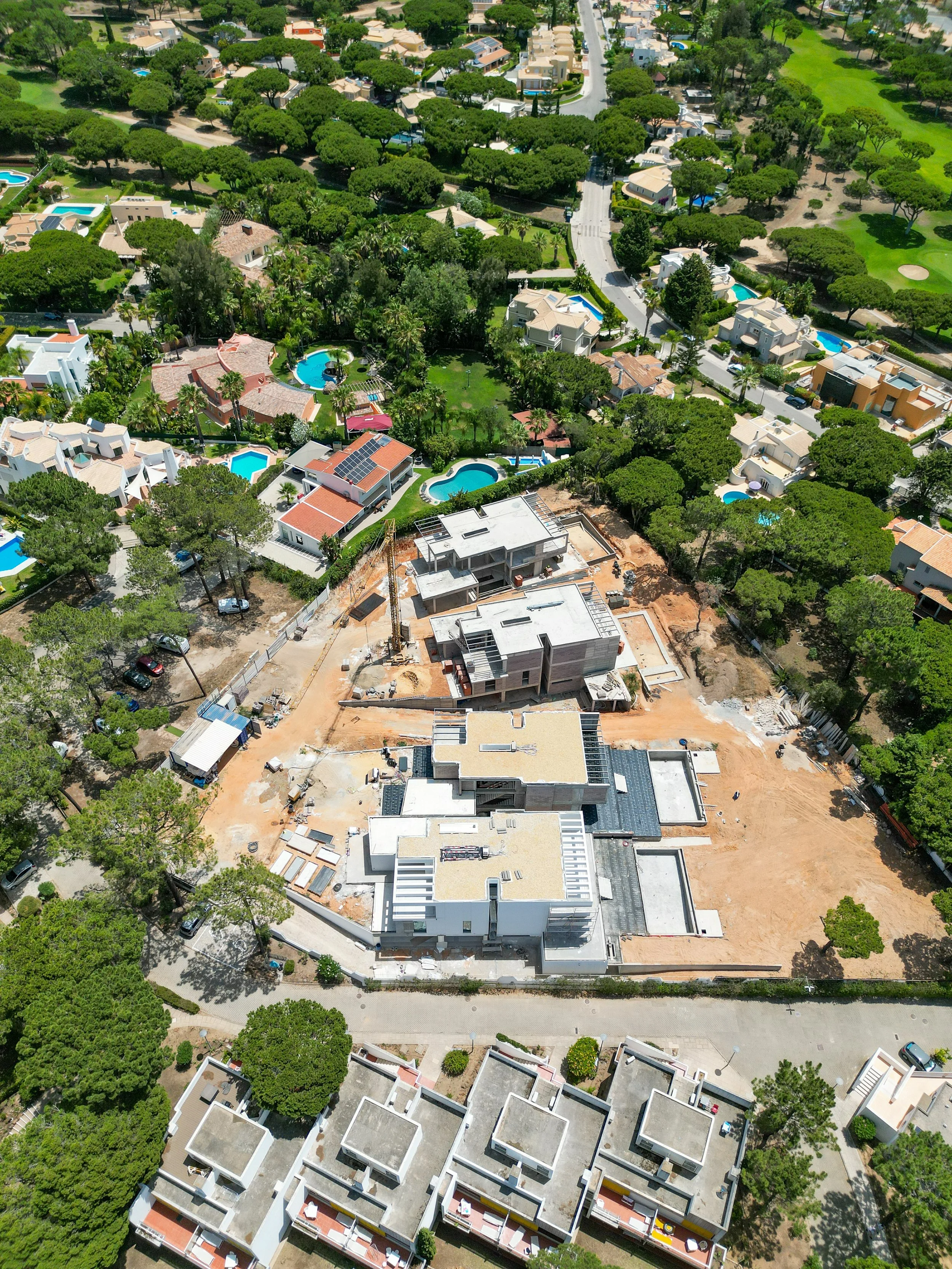 Construção de uma casa nova em um bairro residencial com árvores verdes e piscinas em algumas casas próximas.