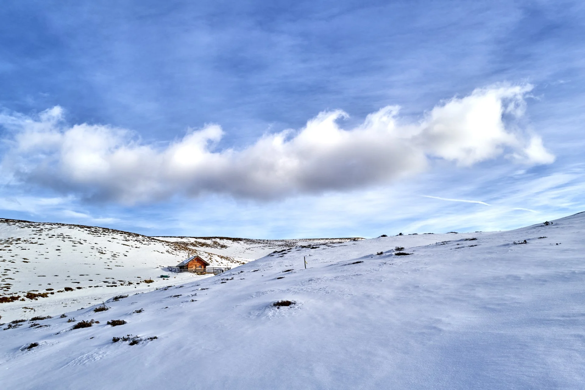 Sicht auf die Hütten von Culm Ault nahe dem Dreibündenstein in einer winterlichen Landschaft mit einer markanten Wolke. Kein Windpark Dreibündenstein.