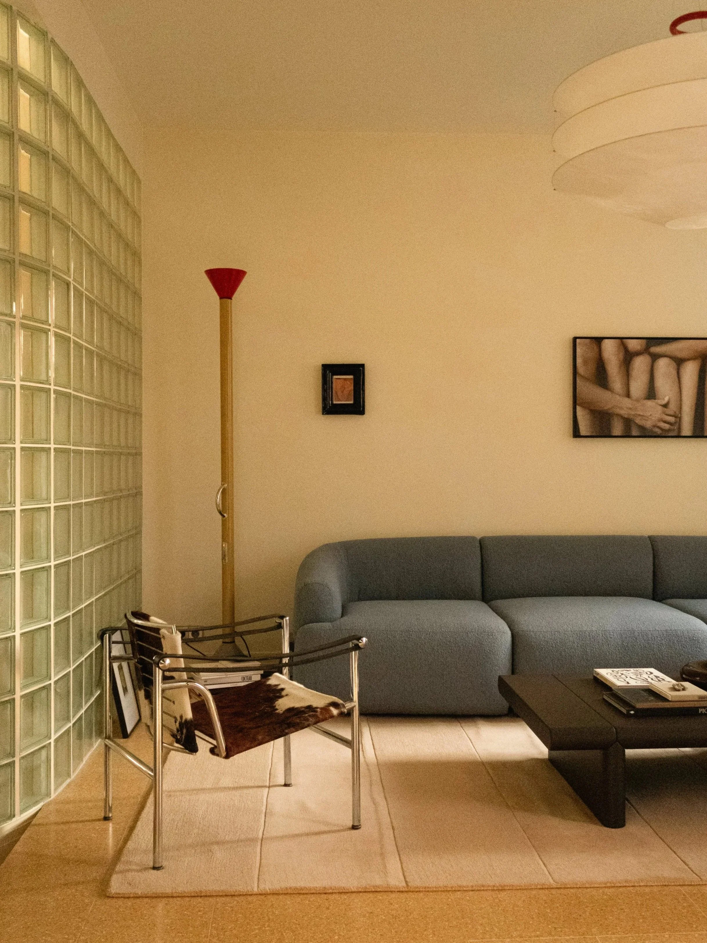 Salon avec un canapé bouclette bleue, une chaise LC1 en peau de vache, une lampe design Artemide.